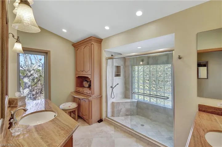 Bathroom with vanity, an enclosed shower, vaulted ceiling, and a wealth of natural light