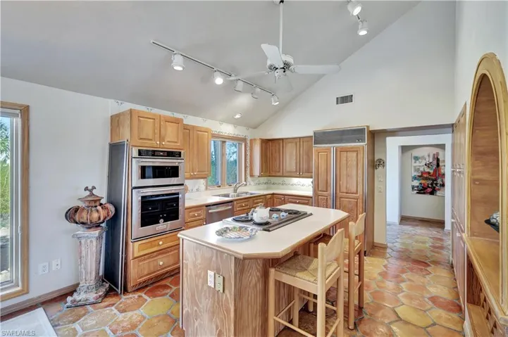Kitchen featuring sink, ceiling fan, appliances with stainless steel finishes, a kitchen breakfast bar, and a kitchen island