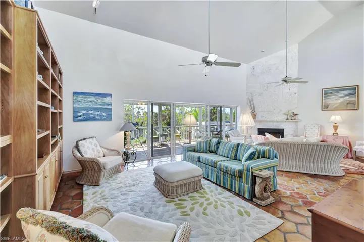 Living room featuring ceiling fan, a fireplace, and high vaulted ceiling