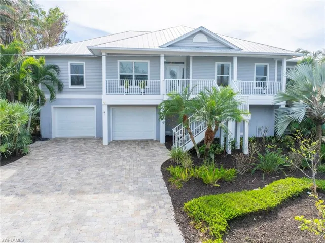 Raised beach house featuring a porch and a garage