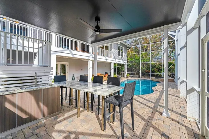 View of swimming pool with a lanai, ceiling fan, an outdoor wet bar, and a patio
