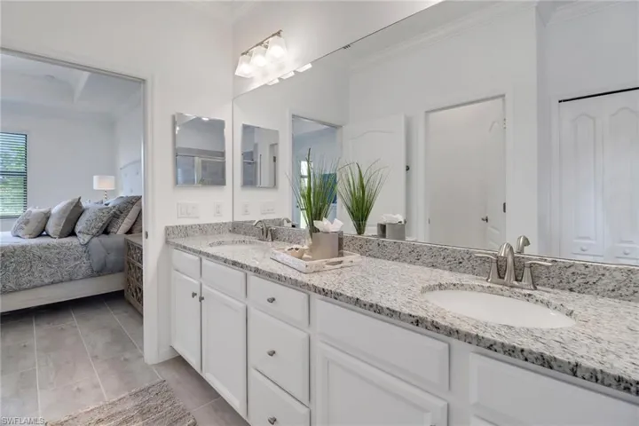 Bathroom with dual vanity, crown molding, and tile patterned flooring