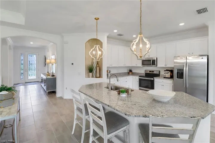 Kitchen with stainless steel appliances, hanging light fixtures, white cabinets, sink, and light and beautiful countertops