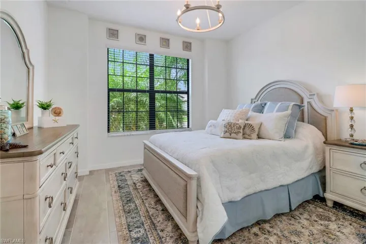 Tiled bedroom featuring a notable chandelier and multiple windows