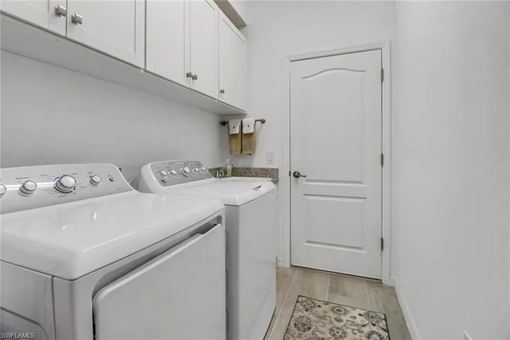 Laundry room featuring sink, washer and dryer, light hardwood / wood-style flooring, and cabinets