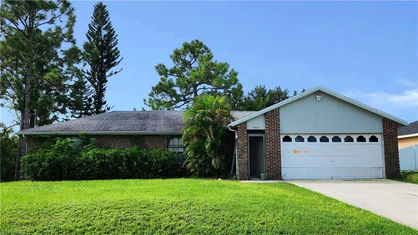 Ranch-style home featuring a front yard and a garage