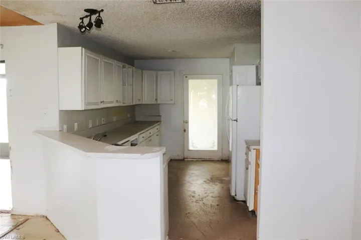 Kitchen with kitchen peninsula, white refrigerator, and a textured ceiling