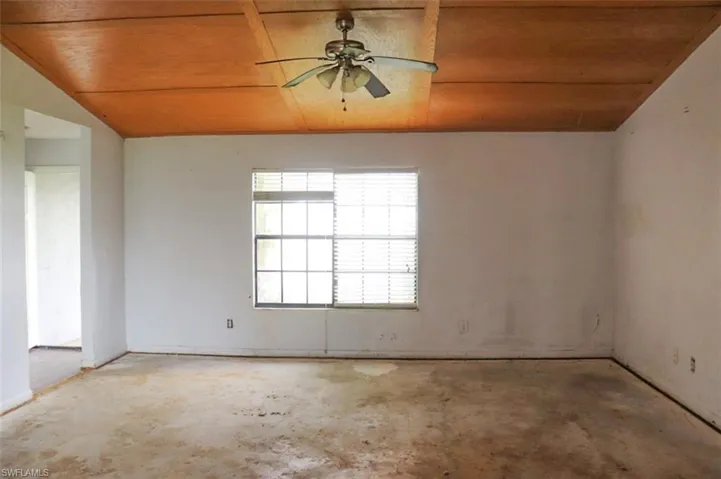 Empty room with ceiling fan, vaulted ceiling, and wooden ceiling