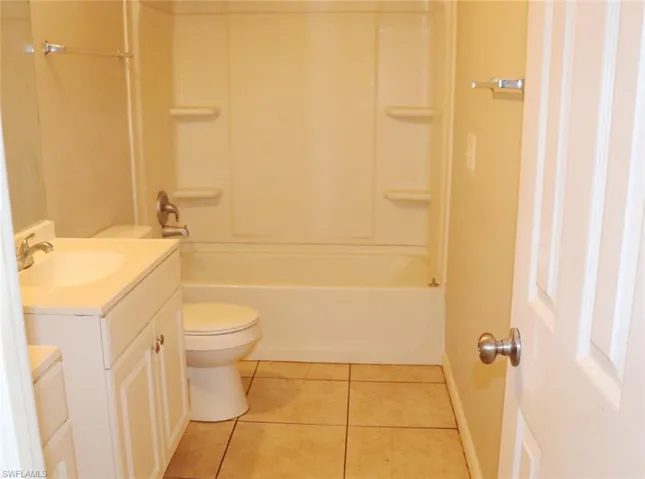 Full bathroom with vanity, toilet, washtub / shower combination, and tile patterned floors