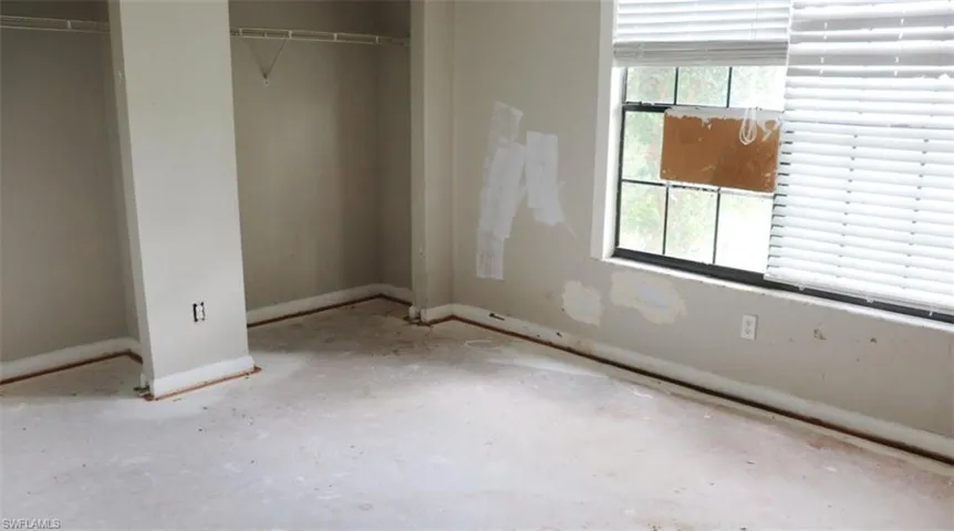 Unfurnished bedroom with concrete floors, a closet, and multiple windows