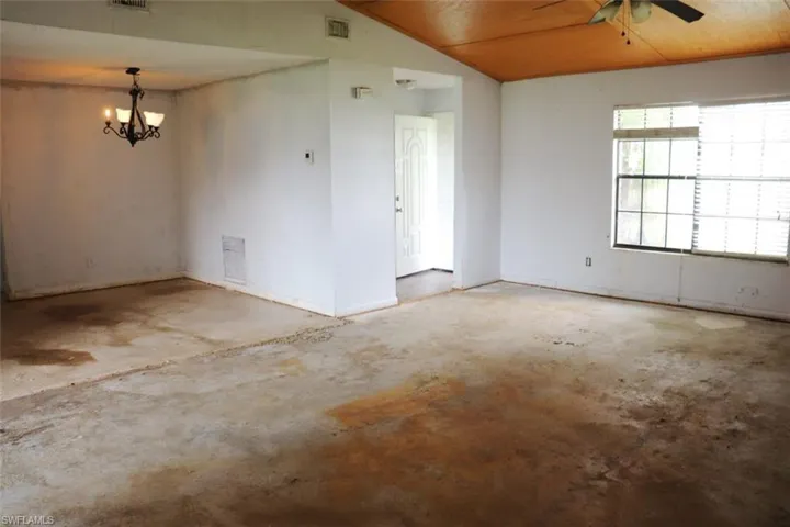 Unfurnished room with lofted ceiling, ceiling fan with notable chandelier, and wood ceiling