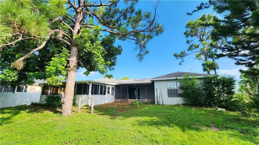Rear view of house featuring a sunroom and a lawn