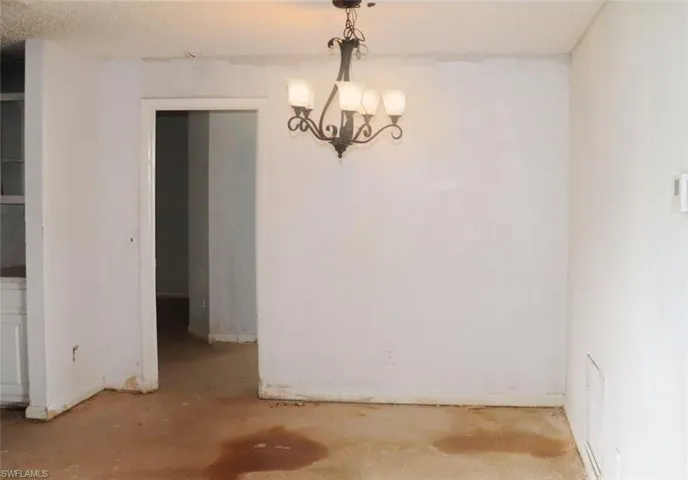 Unfurnished dining area featuring a notable chandelier and a textured ceiling