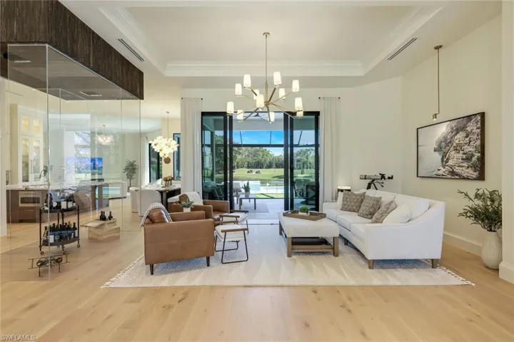 Living room with a tray ceiling, an inviting chandelier, and light hardwood / wood-style flooring