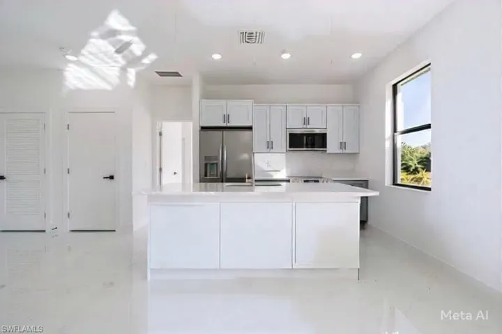 Kitchen featuring stainless steel fridge with ice dispenser and white cabinets