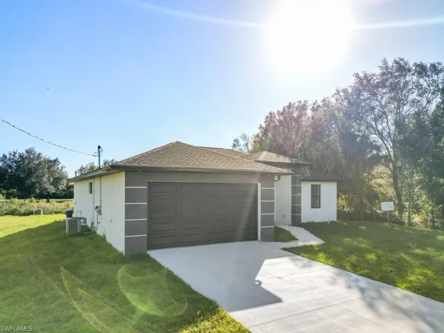 Ranch-style house featuring a front lawn and central air condition unit