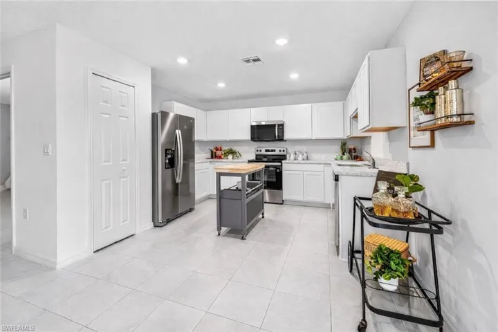 Kitchen with stainless steel appliances, butcher block counters, light tile patterned floors, a kitchen island, and recessed lighting