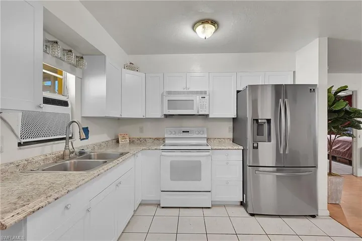 Kitchen featuring white appliances, white cabinetry, and light tile patterned floors