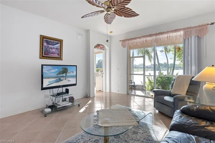 Living room with tile floors, ceiling fan, and a healthy amount of sunlight