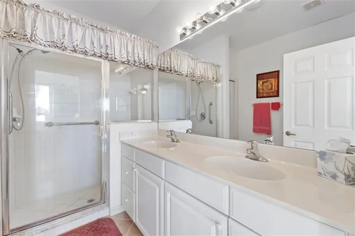 Master Bathroom with an enclosed shower, tile flooring, vanity with extensive cabinet space, and dual sinks