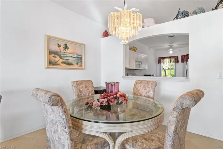 Tiled dining area with ceiling fan with notable chandelier