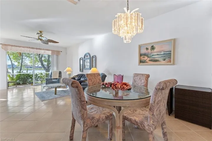 Tiled dining area with a water view and ceiling fan with notable chandelier