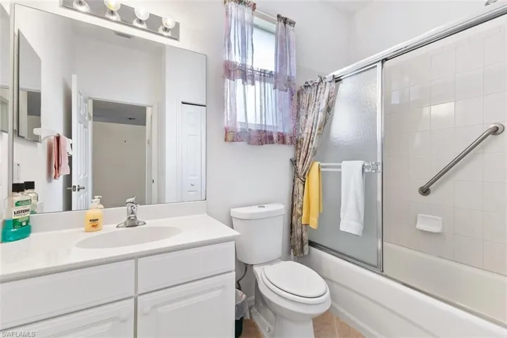 Full bathroom featuring tile flooring, toilet, bath / shower combo with glass door, and large vanity