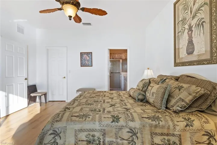 Bedroom featuring hardwood / wood-style floors, ceiling fan, and ensuite bath