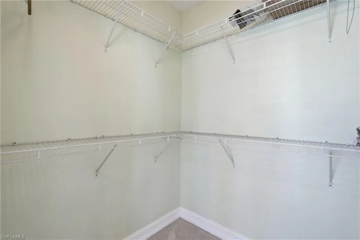 Walk-in closet with wire shelving and wall-mounted hanging rods - Virtually Edited Image