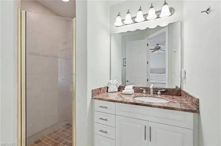 White vanity with a built-in sink, stone countertop, and brushed nickel fixtures - Virtually Edited Image