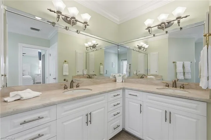 Dual vanity with individual sinks, extensive countertop space, white cabinetry, integrated mirrors, and decorative light fixtures - Virtually Edited Image