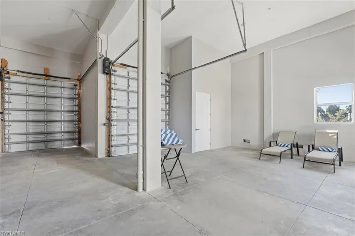 Spacious interior with high ceilings, concrete flooring, and multiple roll-up garage doors - Virtually Edited Image