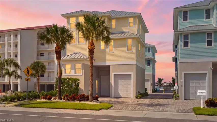 Modern coastal residence featuring a striking cream and black exterior with metal roof accents, flanked by mature palm trees - Virtually Edited Image