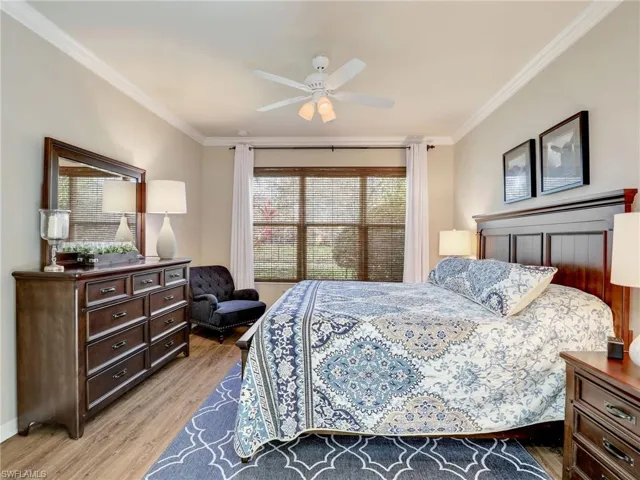 Bedroom featuring light wood-type flooring, crown molding, baseboards, and ceiling fan