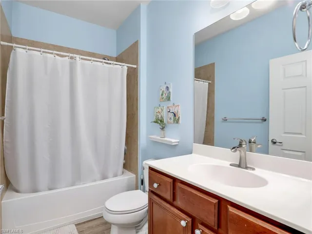 Full bathroom featuring toilet, vanity, and shower / bathtub combination with curtain