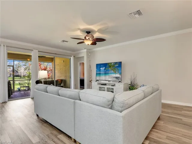 Living room with ornamental molding, visible vents, and light wood-style floors