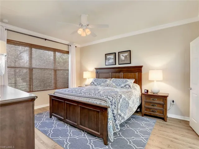 Bedroom with light wood finished floors, ceiling fan, baseboards, and crown molding