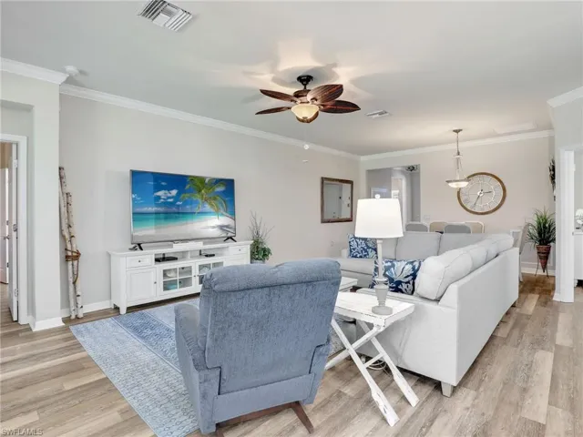 Living area with ornamental molding, visible vents, and light wood-style flooring