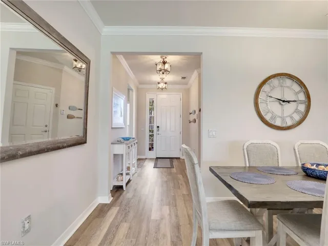 Entrance foyer with light wood-type flooring, baseboards, ornamental molding, and a notable chandelier