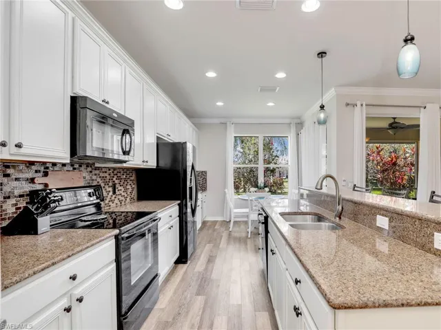 Kitchen featuring black appliances, ornamental molding, decorative backsplash, and a sink