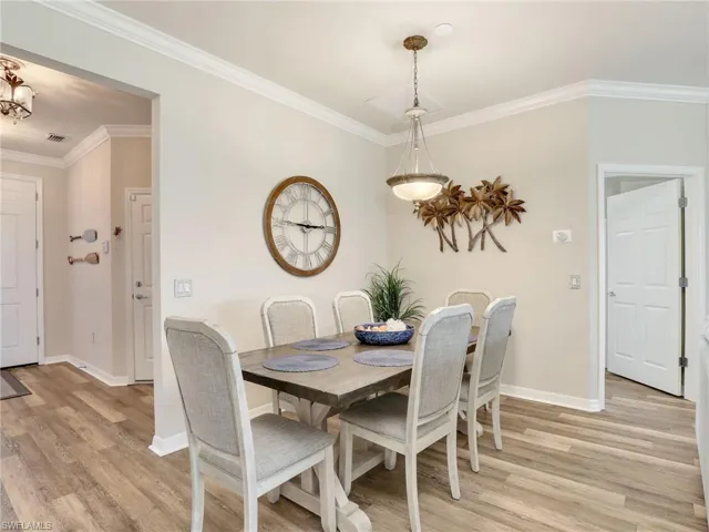 Dining area with light wood-type flooring, crown molding, and baseboards