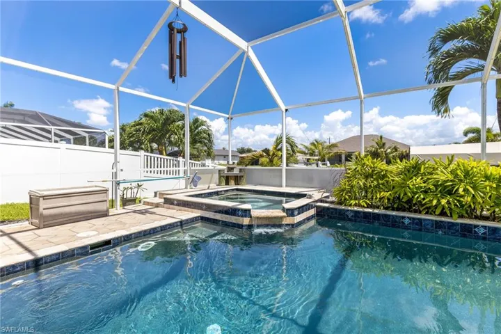 View of pool with glass enclosure and an in ground hot tub
