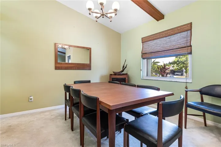 Dining area with an inviting chandelier, carpet flooring, and vaulted ceiling with beams