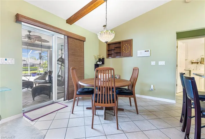 Dining room featuring vaulted ceiling with beams, light tile floors, and ceiling fan