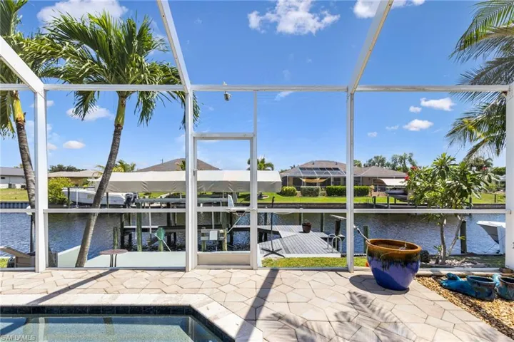 View of swimming pool featuring a boat dock, glass enclosure, and a water view