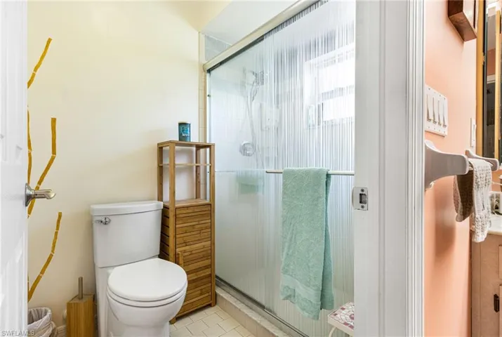 Bathroom featuring tile flooring, a shower with shower door, and toilet