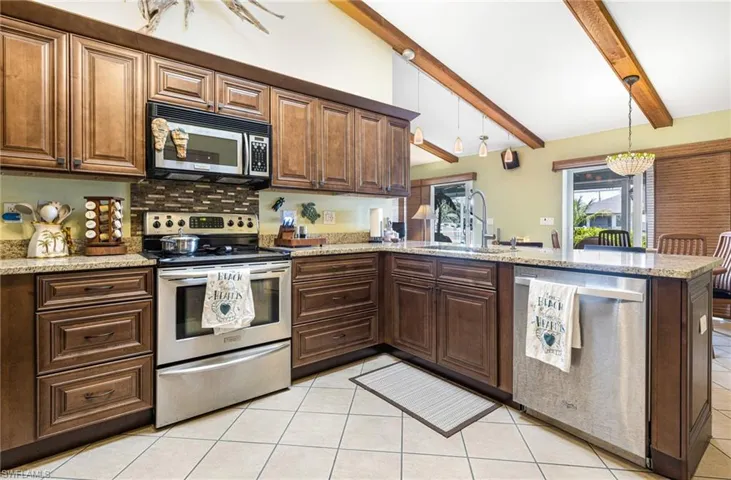 Kitchen with appliances with stainless steel finishes, sink, kitchen peninsula, and light tile floors