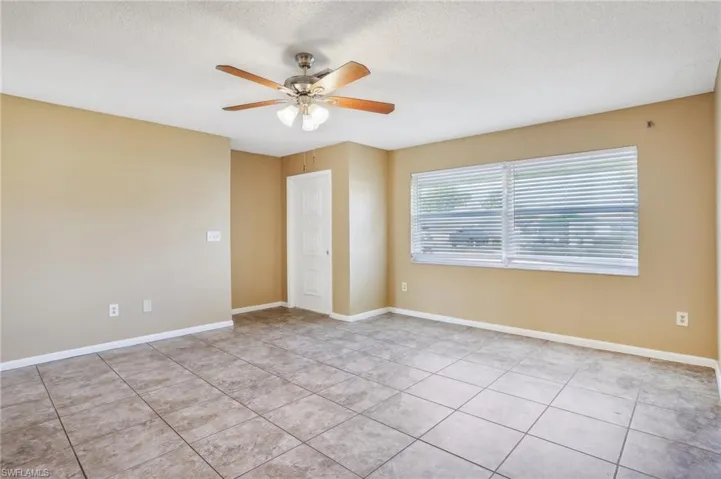 Unfurnished room with a textured ceiling, light tile flooring, and ceiling fan