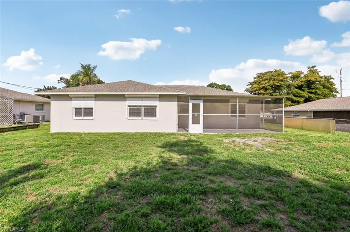 Back of property featuring a sunroom, a lawn, and central air condition unit