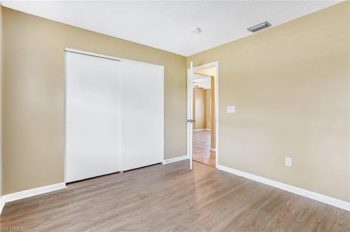 Unfurnished bedroom featuring a closet, light hardwood / wood-style floors, and a textured ceiling